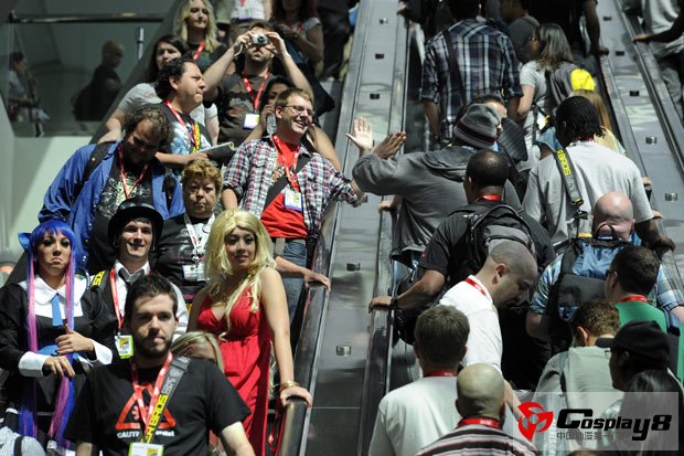 Two people give a high-five as they move up and down an escalator on the first day of  Comic Con 2011