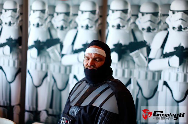 An attendee dressed as Darth Vader sleeps at the 501st legion booth